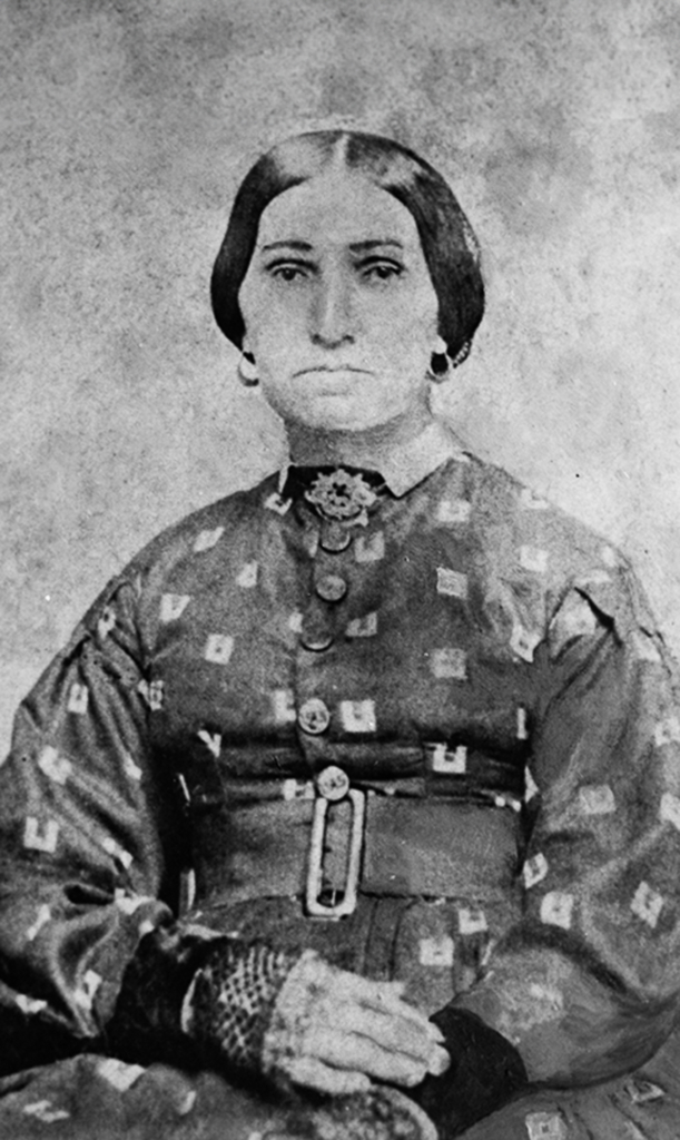 Black and white portrait of a woman wearing a high-necked patterned dress and a belt with a wide buckle.
