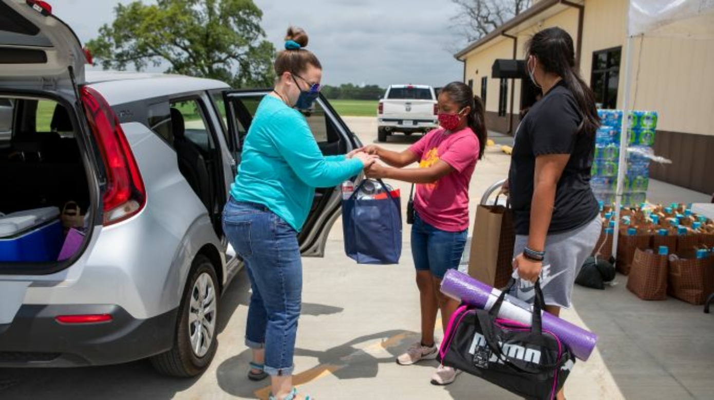 CPN Workforce Development and Social Services staff hand bags of supplies to clients in the building's parking lot.
