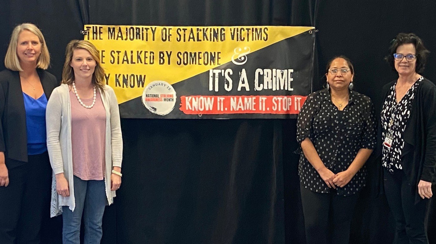 CPN House of Hope's Kayla Woody stands with leaders from the National Stalking Prevention Awareness and Resource Center in front of a banner that reads "The majority of stalking victims are stalked by someone they know. It's a crime. Know it. Name it. Stop it."
