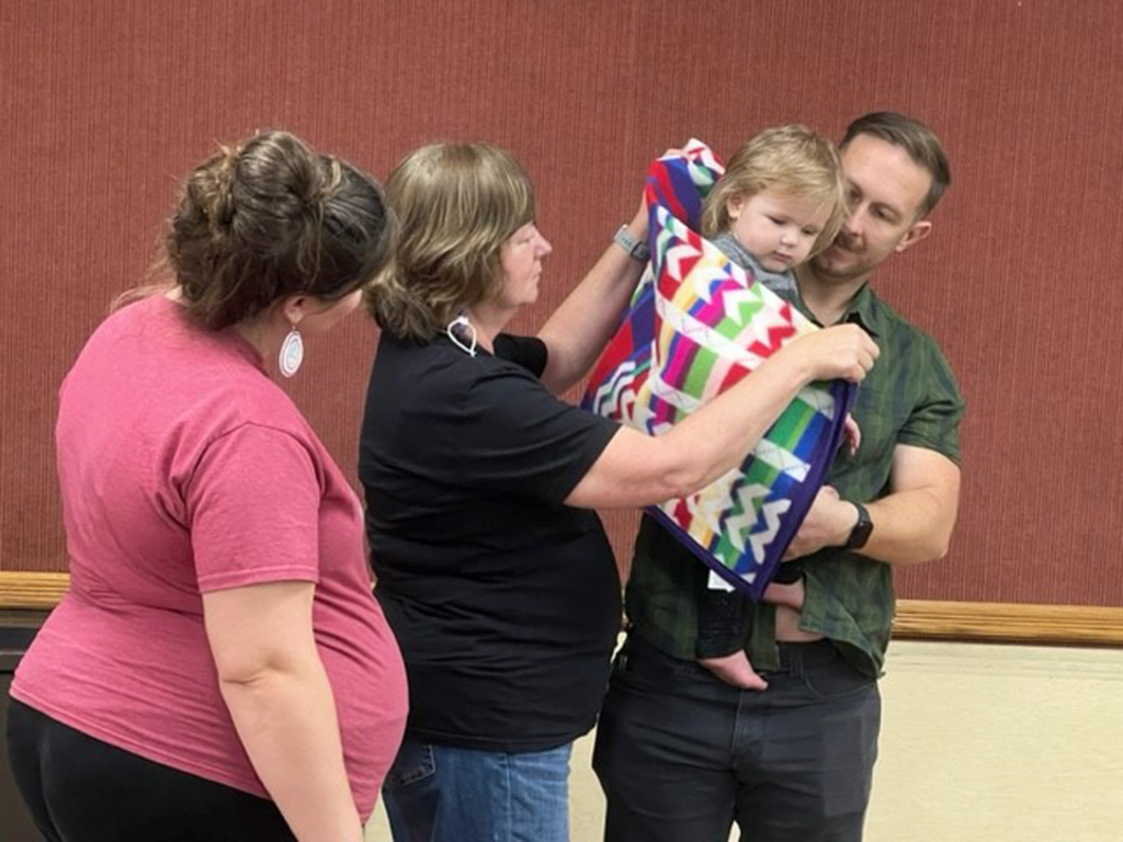 Aurora, our youngest attendee, is awarded a crib blanket.