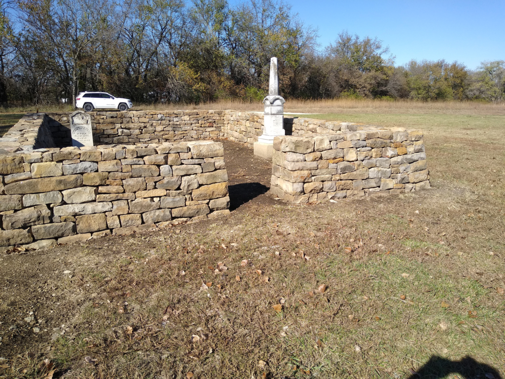 A photo of a neatly stacked stone wall around a cemetery.
