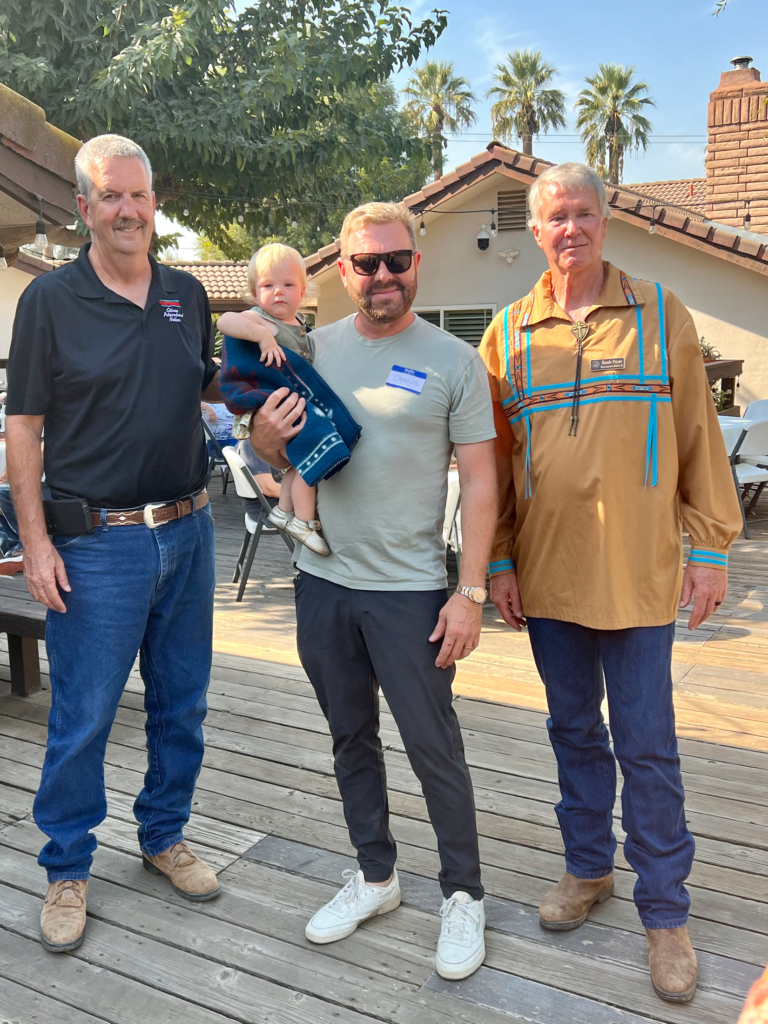 Two CPN Legislators stand with a father holding a young child.