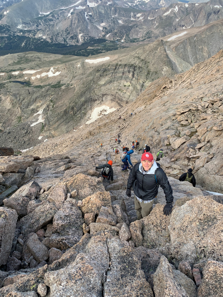 Photo from above of Steve Lawson climbing a steep cliff towards the top of Longs Peak.