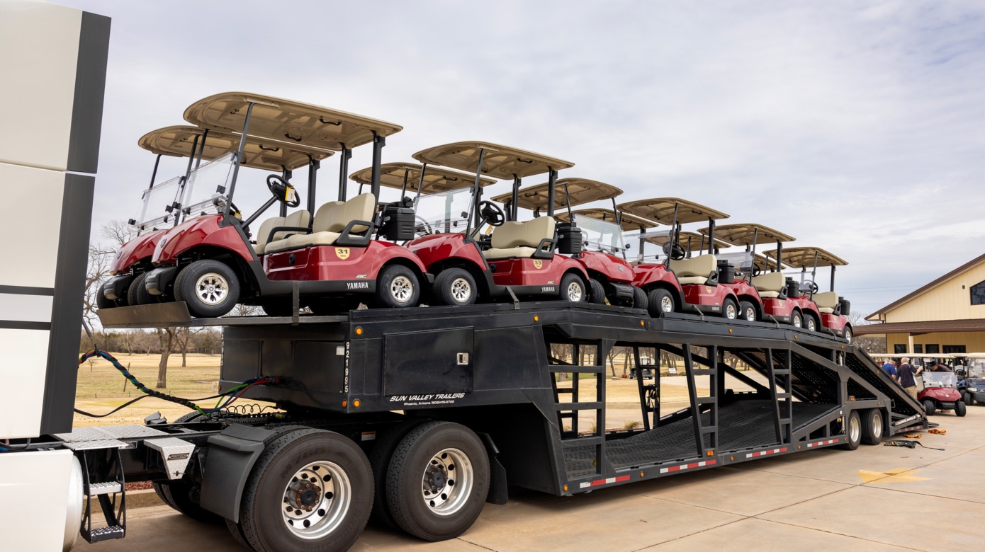 A dozen new red golf carts arrive at FireLake Golf Course on a trailer.