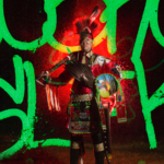 One of Aptiz's lenticular prints featuring a full body shot of someone in full regalia with bright green letters surrounding the figure and a red light coming from them.