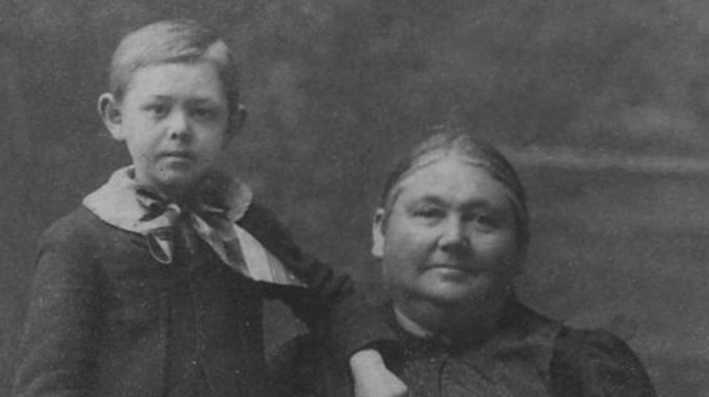 Archival black and white photo of a woman, seated, and a young child standing next to her.