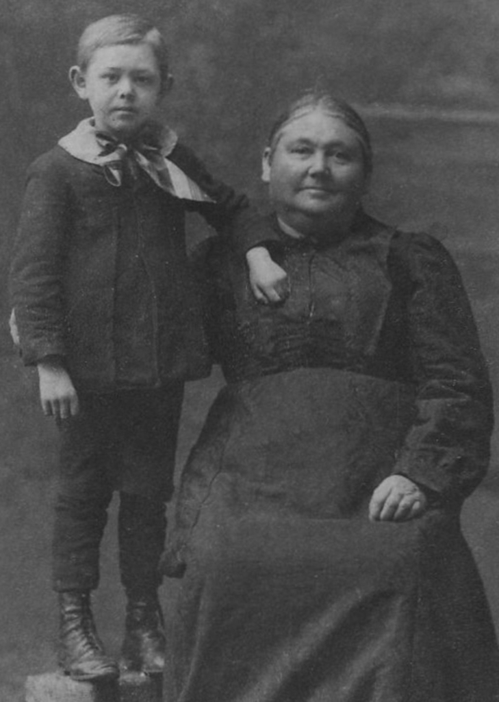 Archival black and white photo of a woman, seated, and a young child standing next to her.