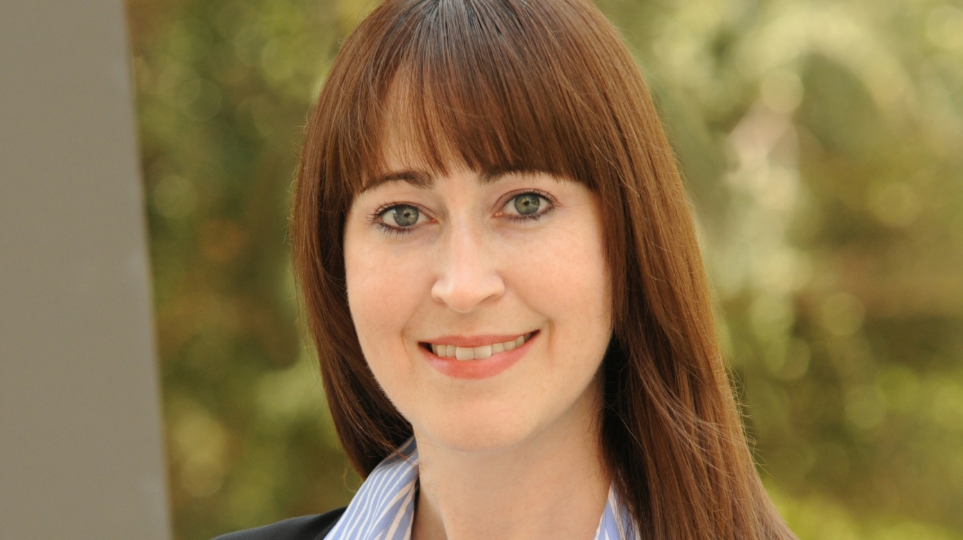 Headshot of CPN Supreme Court Associate Justice Jennifer Lamirand in a blue and white striped blouse and black blazer. Her reddish hair contrasts with the greenery of the background.