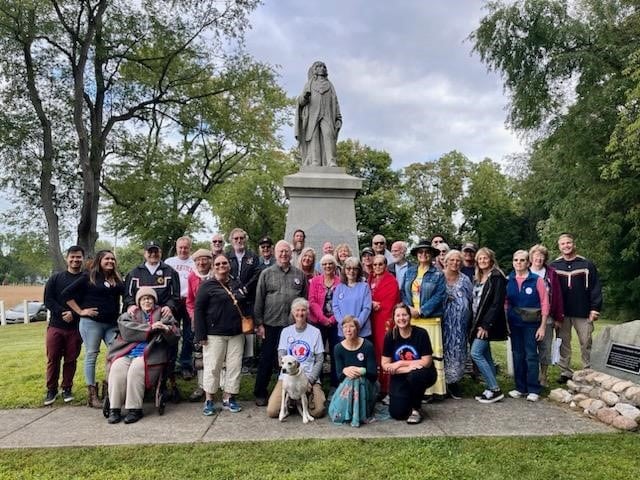 Group photo in front of a stone statue of Chief Menominee.