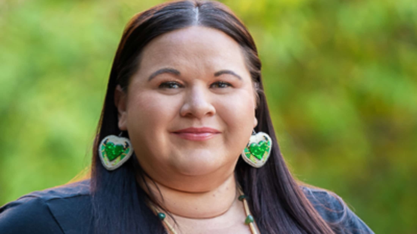 Headshot of Kendra Lowden. She wears a black shirt, with accenting green beaded earrings and necklace.