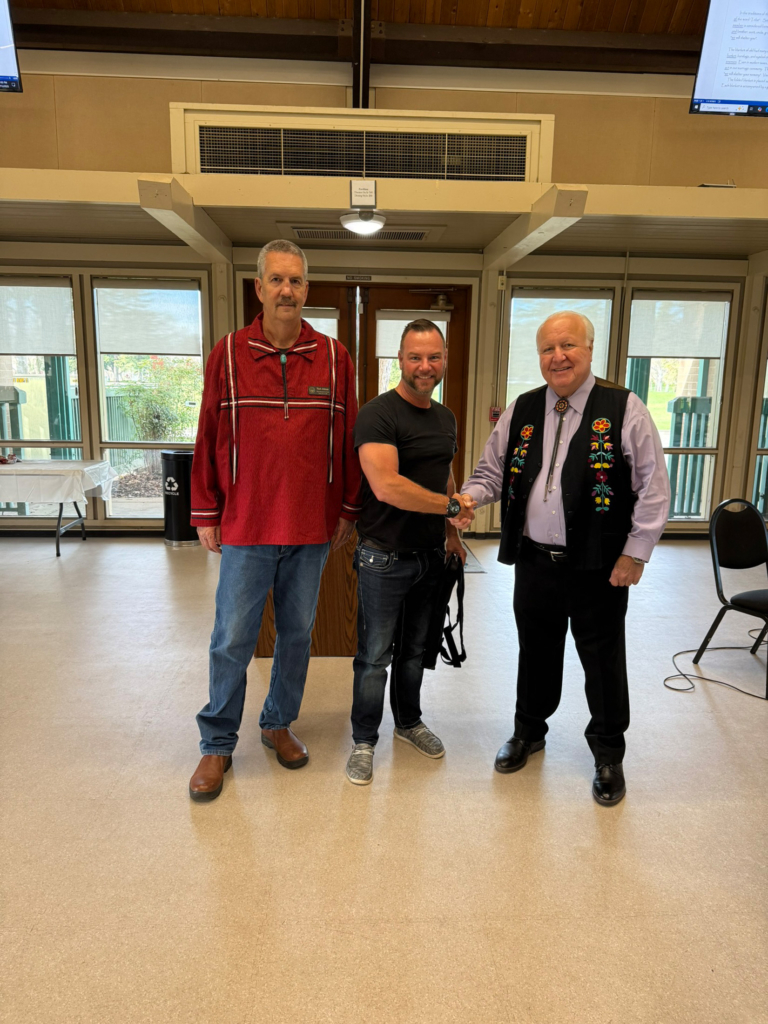 Tribal Chairman John "Rocky" Barrett shakes hands with Tribal member Bill Lackey. Mark Johnson joins them on the left side of the frame.