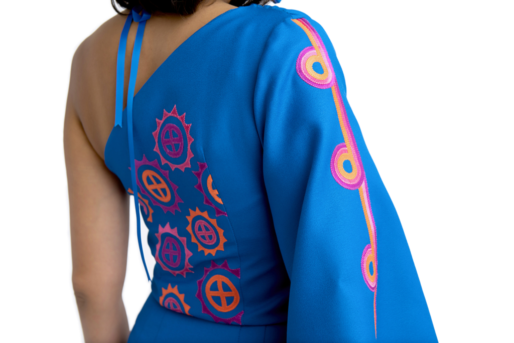 An example of Mound Builder themes that Deer works to preserve in her work. Pink and orange patterns of circles divided into four quadrants and circles with triangles lining the outside appear against a bright blue sleeve and back.
