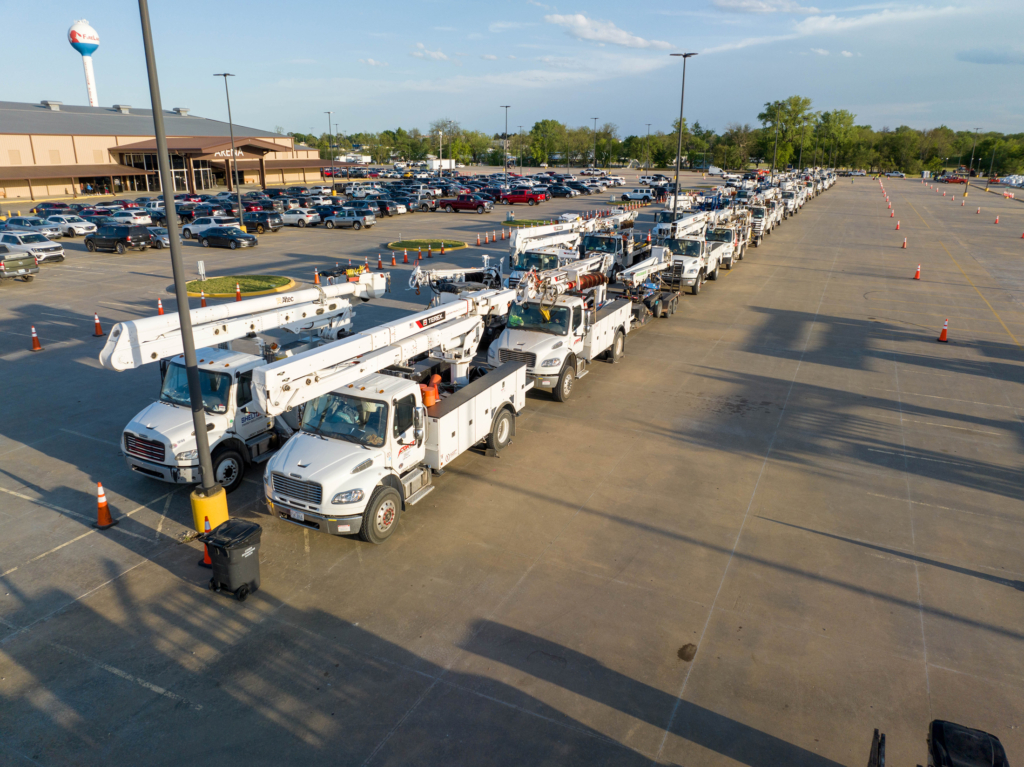 Aerial shot of rows of powerline repair vehicles parked in the FireLake Arena parking lot