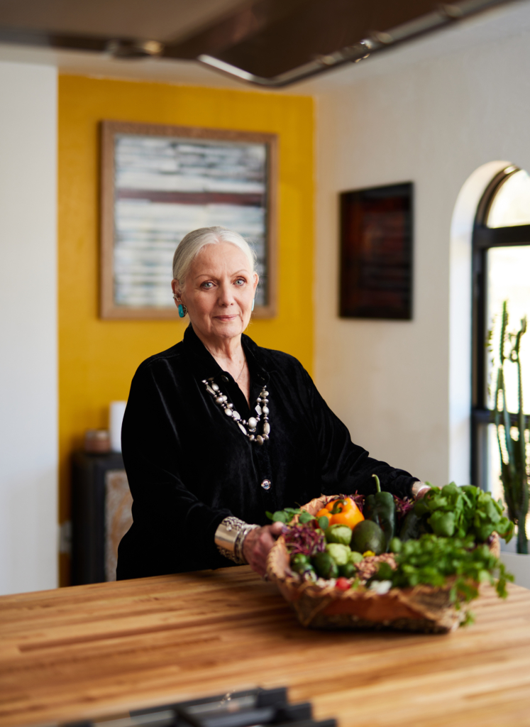 Portrait of chef Loretta Barrett Oden holding a basket of peppers and herbs.