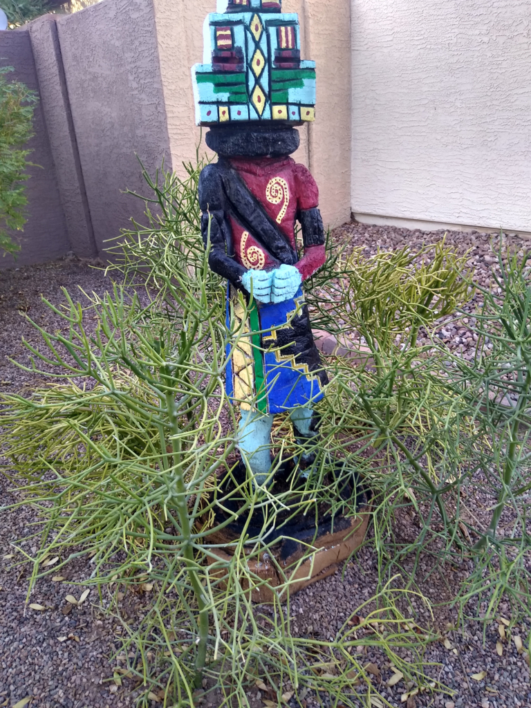 A large wood Kachina painted in light blue, yellow, red, black, and bright blue.