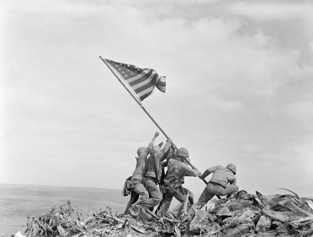 Iconic black and white photo from the Battle of Iwo Jima featuring several U.S. soldiers raising an American flag.