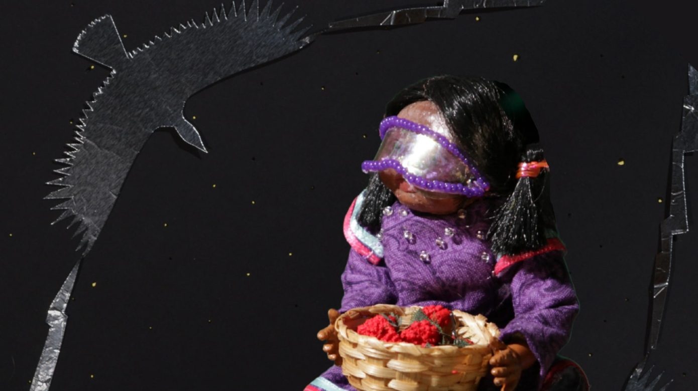 Film poster for "Speak Again," featuring the stop-motion child doll dressed in colorful clothing and holding a basket of strawberries made out of paper. The subtitle reads "Where once a nation spoke as one, we will speak again." "Speak Again" is a collaboration between Citizen Potawatomi artists Nicole Emmons and Elexa Dawson.