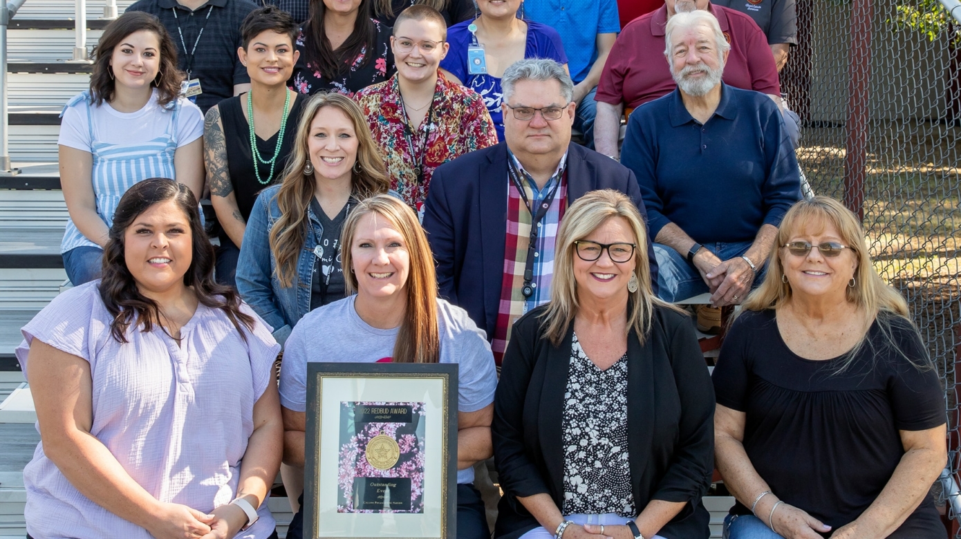Members of the 35-person Fireflight Balloon Fest event committee sit in the CPN Dance Arena stands. Dennette Summerlin, CPN Administrative Assistant, holds the RedBud Award plaque for Outstanding Event.