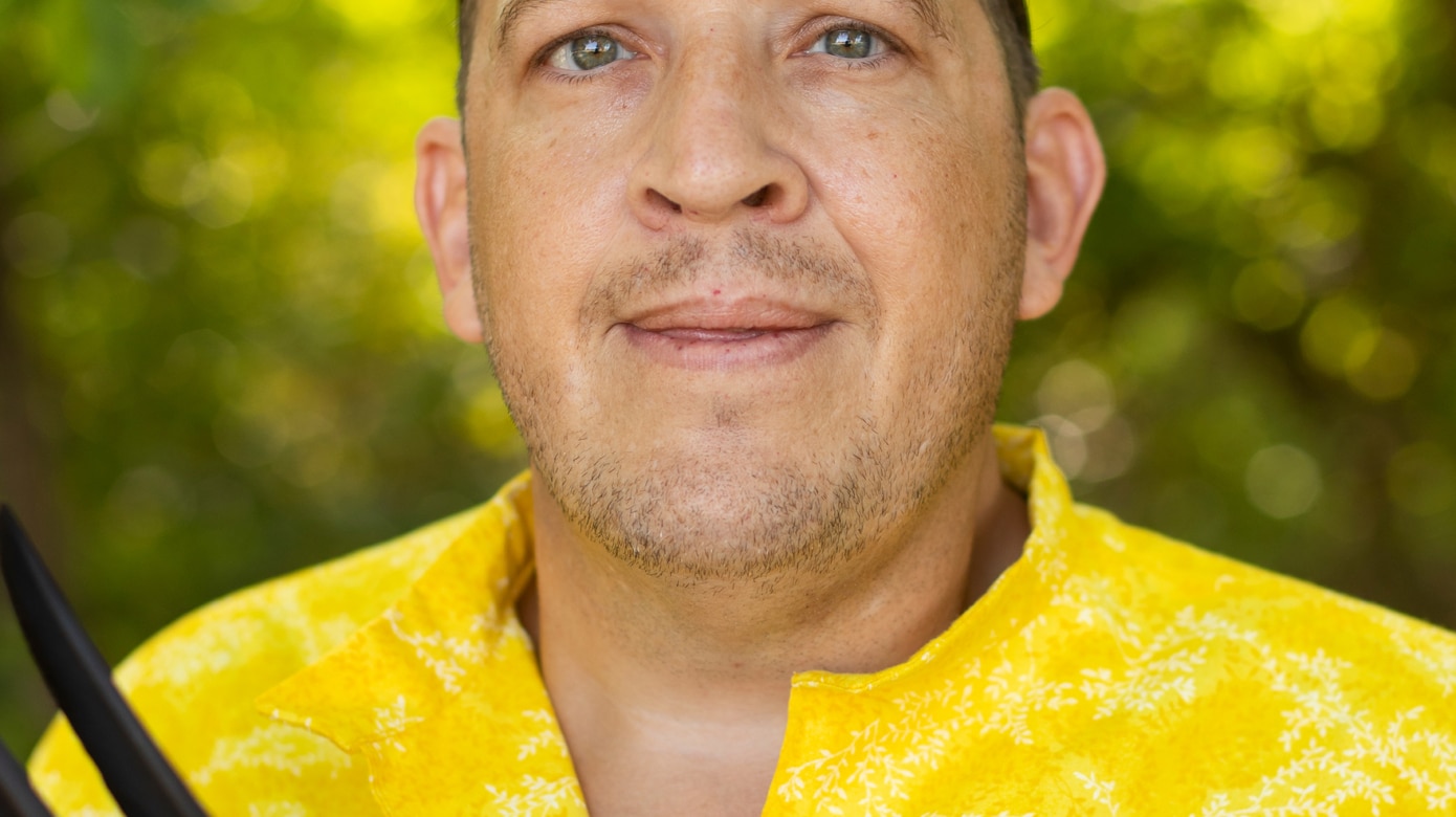 Headshot of Language Aide Robert Collins wearing a bright yellow shirt with red ribbons.