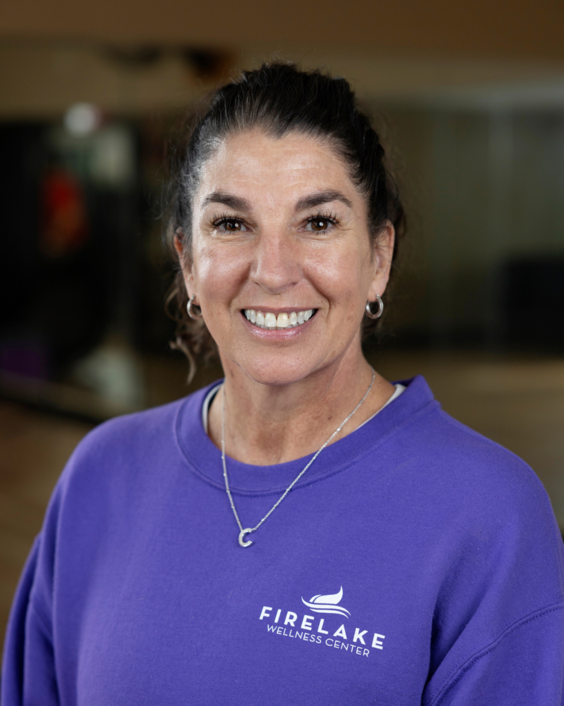 Headshot of CPN FireLake Wellness Center, Leslie Cooper. Cooper wears a purple Wellness Center t-shirt, a small pendant necklace, and her dark hair pulled back into a ponytail.