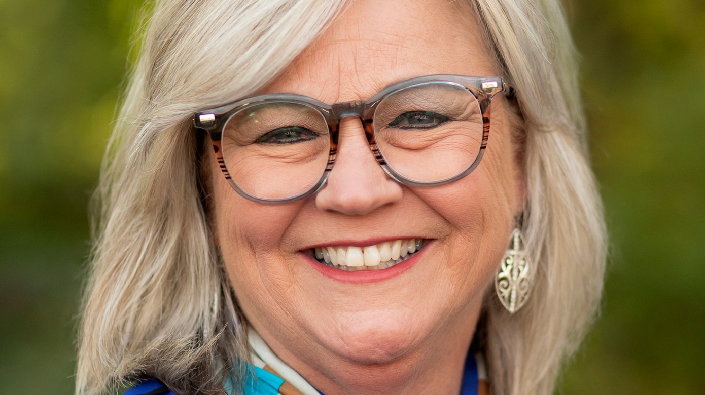 Headshot of CPN Director of Employee Advocacy, Kelley Francen. Francen wears a brilliant blue blouse with accenting silk scarf. She has shoulder-length blonde hair and her eyes smile behind large brown glasses frames.