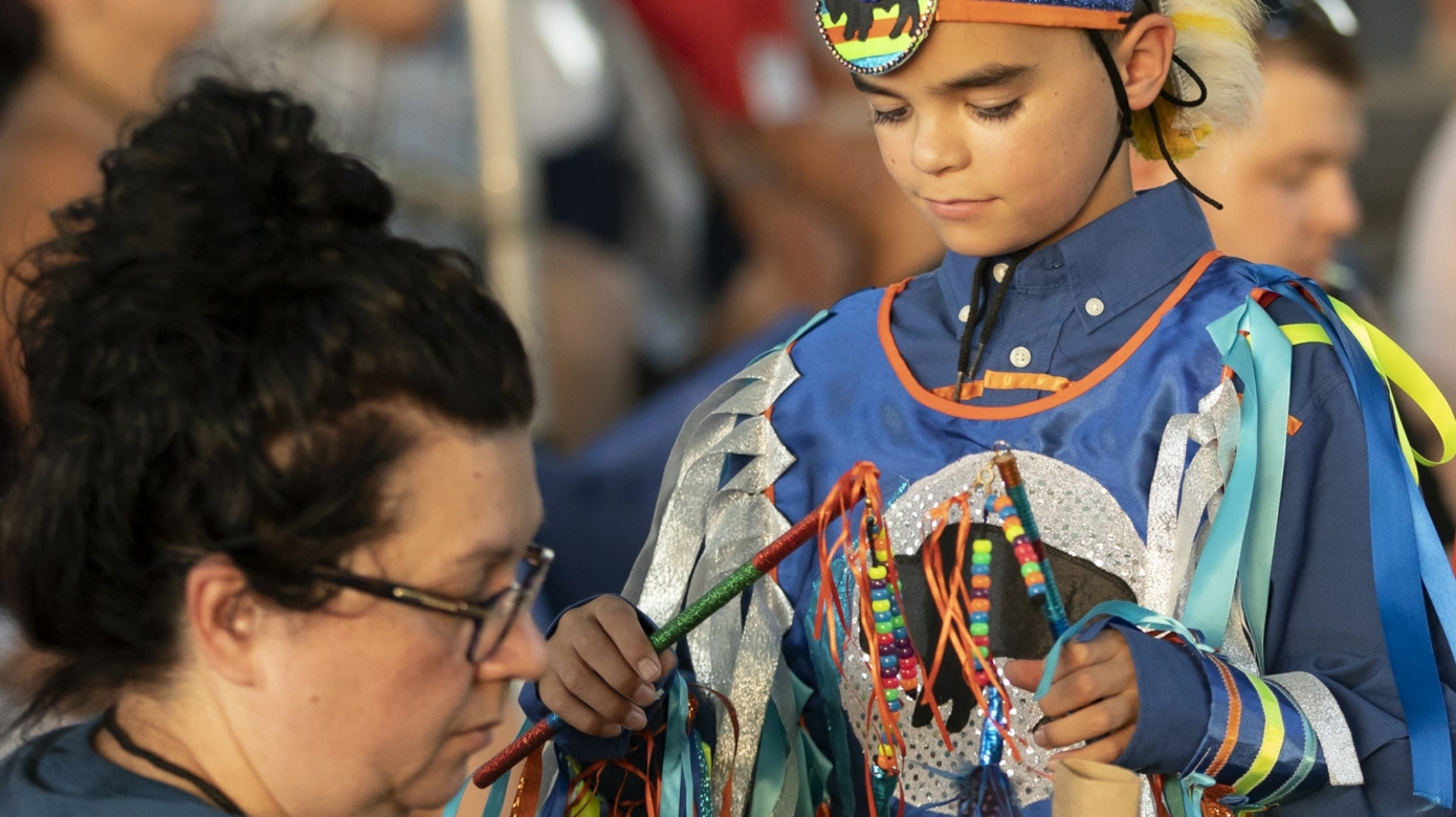 A young Tribal member receives assistance with their regalia at Family Reunion Festival 2022.