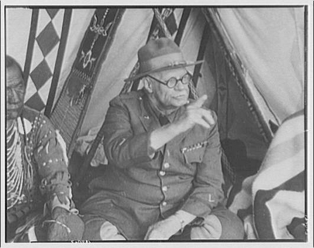 Black and white photo of a seated person communicating in Plains Indian Sign Language.