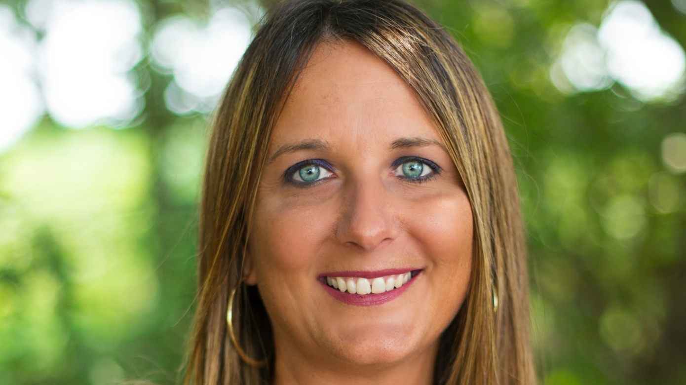Headshot of CPN Office of Self-Governance Director Kasie Nichols, with green leaves of a tree out of focus in the background.