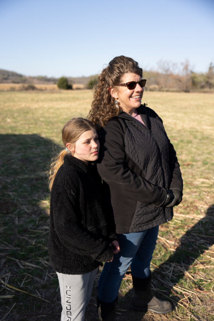 Sarah and Hope Pappan stand together in the sun, overlooking the farm.