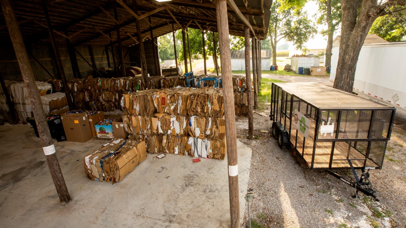 Bales of cardboard stacked in a two-sided barn.