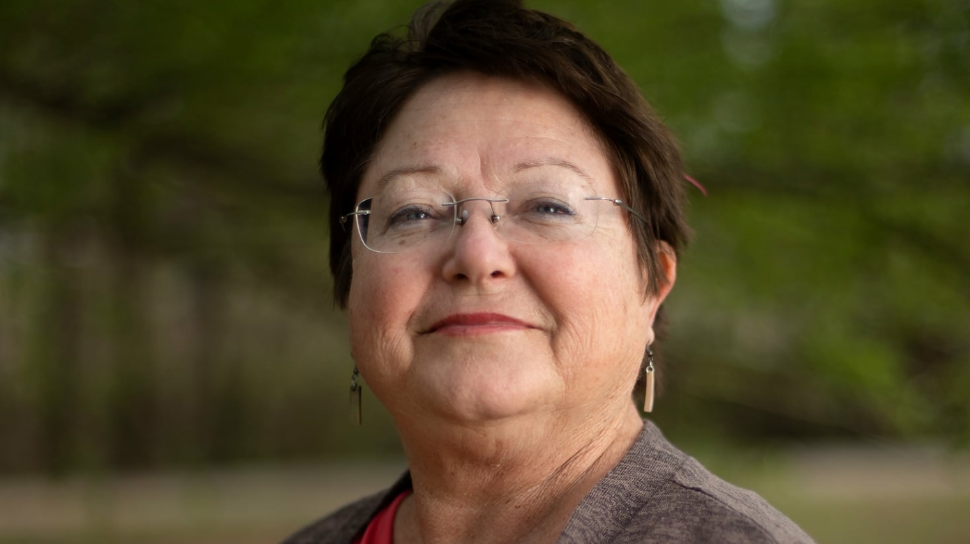 Headshot of CPN Workforce and Social Services Director Margaret Zientek. She wears muted red lipstick and frameless glasses, and stands in front of trees which are out of focus in the background.
